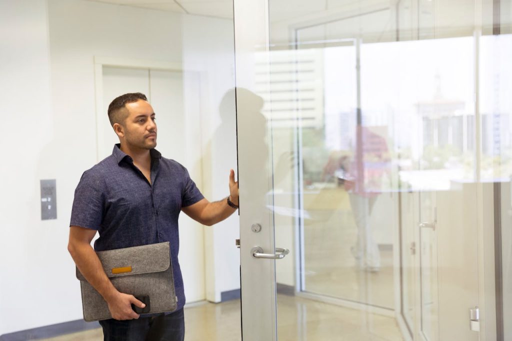 Man entering a modern office through a glass door, reflecting professionalism and modern design.