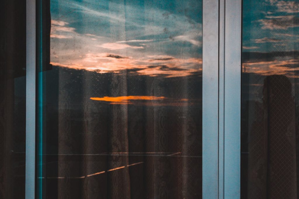 Reflective sunset captured through glass doors, showcasing a tranquil sky with vivid colors.